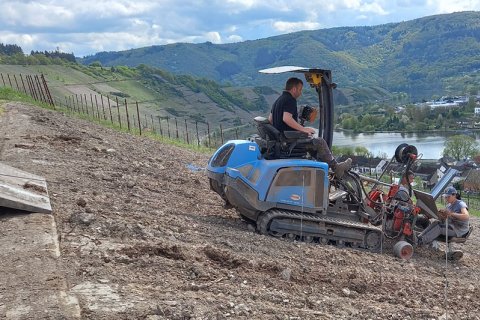 Weinbergsarbeit beim Pflanzen mit der Raupe. Zwei Personen auf Raupe.