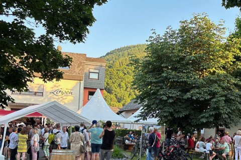 Impression Hoffest Impression vom Hoffest mit Blick von der Straße aus mit Gästen auf der Grünfläche und unter einem Zelt. Im Hintergrund ist das Weingut mit Pagodenzelt zu sehen.
